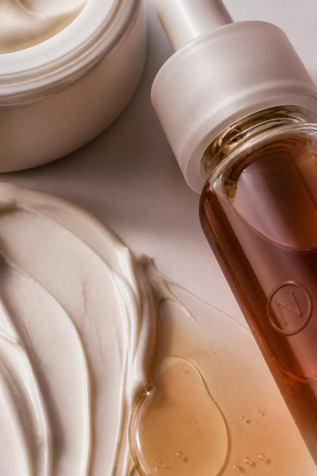 Macro de sérum, verre ambré et texture cosmétique crème — illustration originale du concept Noma Skin (projet fictif).